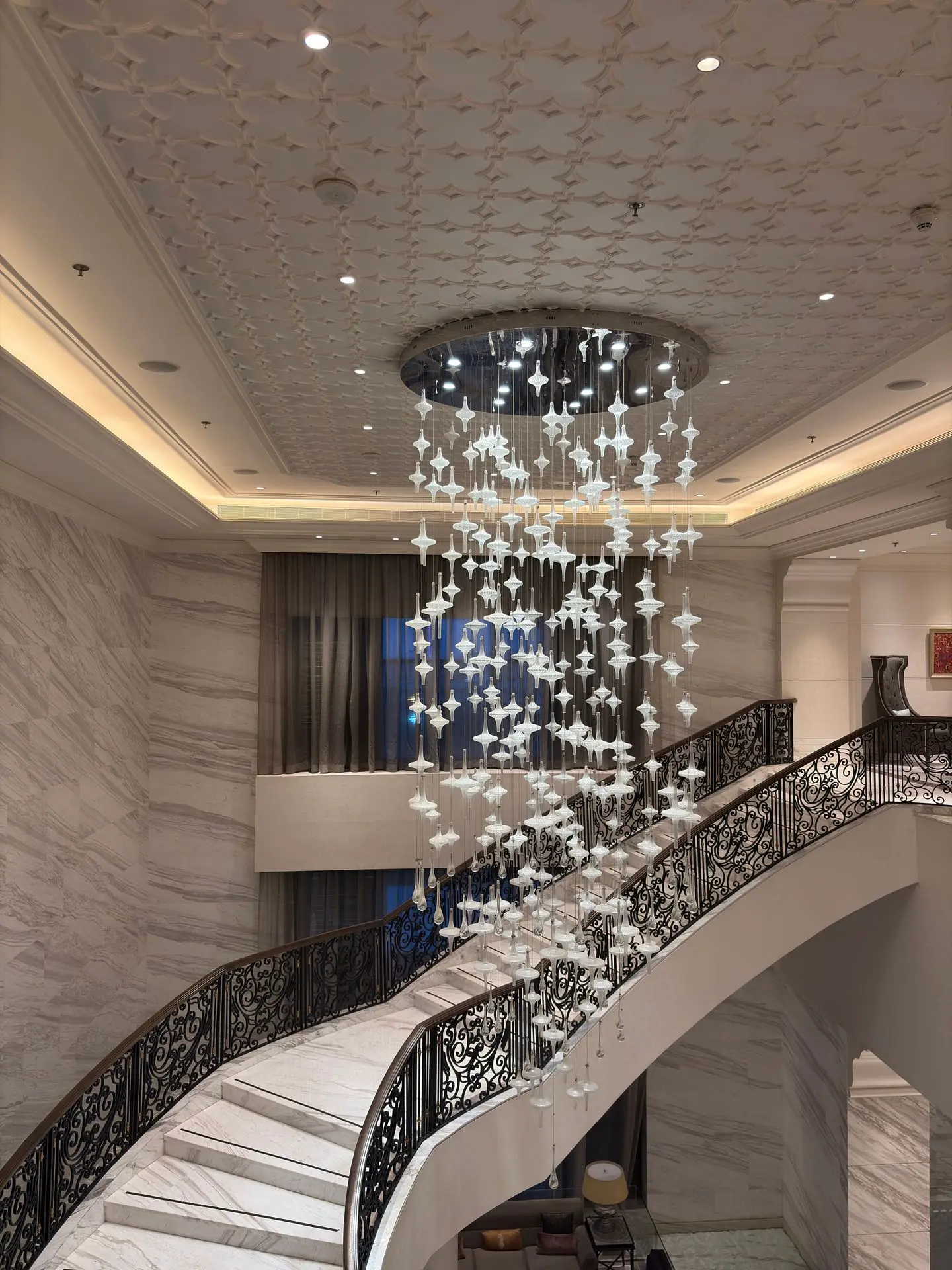 Decorative chandelier installation above an elegant hotel staircase and lobby area