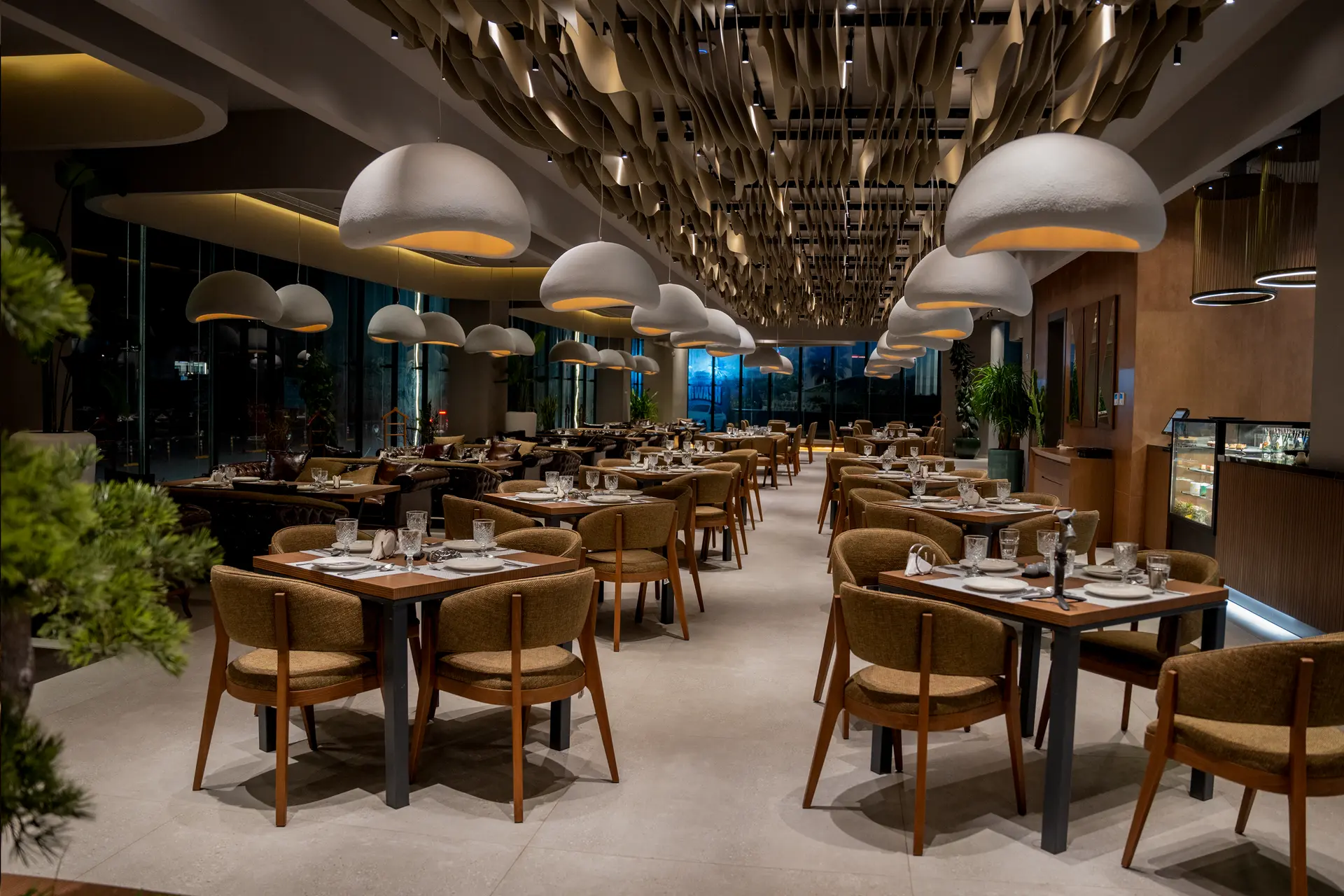 Modern hotel restaurant dining area with tables, chairs and pendant lighting